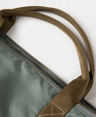Sage green bag with zipper seam and brown webbing strap attachment