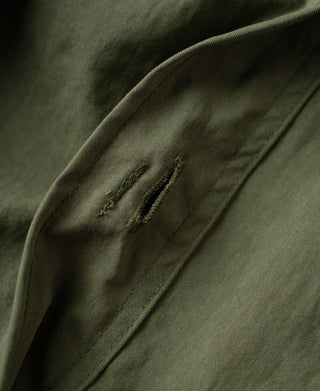 Olive trouser leg with side seam stitching and front pocket edge detail.