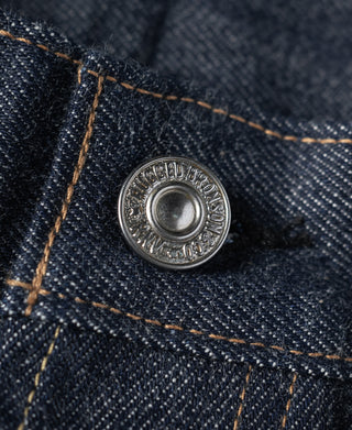 Round silver-toned metal rivet on dark blue denim with contrast orange-brown topstitching