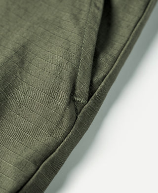 Olive fatigue pants side seam close-up with smooth curved pocket edge