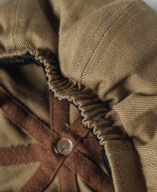 Khaki biker cap side seam with dark knit trim and round snap button.