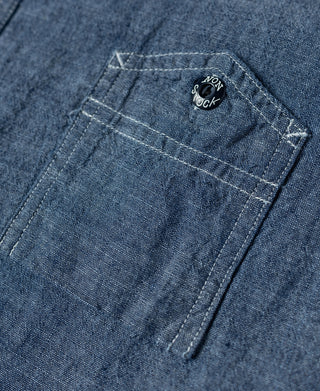 Blue chambray work shirt chest pocket with stitched label patch