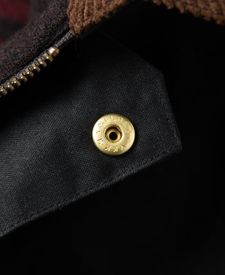 Black waxed jacket with brass snap closure, close-up