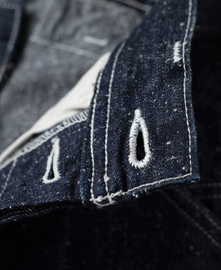 Indigo denim hem patch with white bartacks and embroidered pocket detail