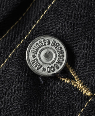 Metal snap button on black tour jacket with gold stitching and textured fabric