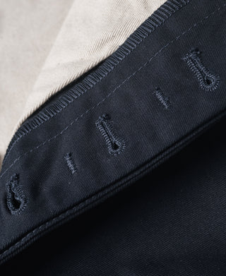 Navy trouser leg cuff with notch-style strap detail and topstitching