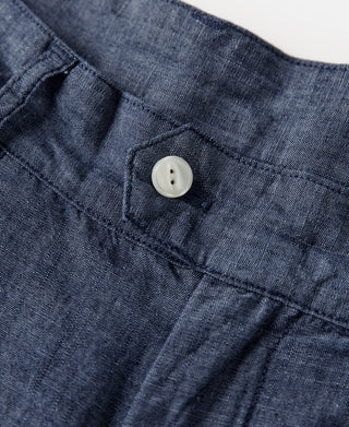 Indigo chambray pants waistband close-up with button and pleat construction