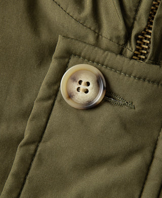 Olive parka close-up: round button on front placket with stitched placket edge