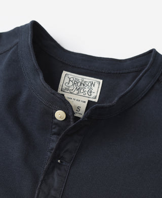 Navy henley shirt neckline with brand tag and button placket opening.