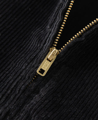 Gold-tone zipper pull and teeth on black corduroy jacket, close-up