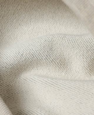 Close-up of gray hoodie fabric texture with off-white ribbed knit edge seam.