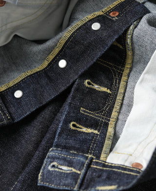 Indigo denim jeans fly area with dark lining, white button accents, and pocket stitching
