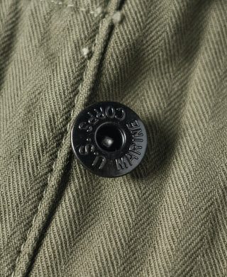 Black button detail on olive utility pants with stamped lettering