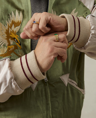 Close-up of green jacket zipper pull and ribbed cuffs with striped knit trim