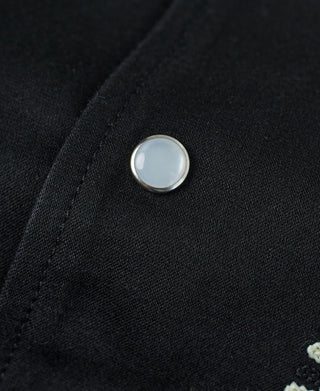 Black jacket close-up of round front button on dark fabric
