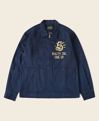 Navy tour jacket front with embroidered chest badge and zip-up stand collar.