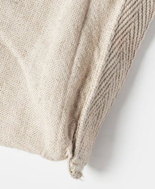 Natural linen tote bag side seam close-up with stitched bottom corner.