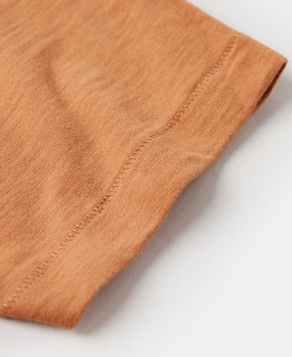 Orange slub cotton t-shirt hem with visible stitched finishing.