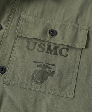 Olive chest pocket close-up with USMC logo and buttoned flap