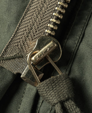 Olive green parka zipper with metal pull and stitched pocket detail