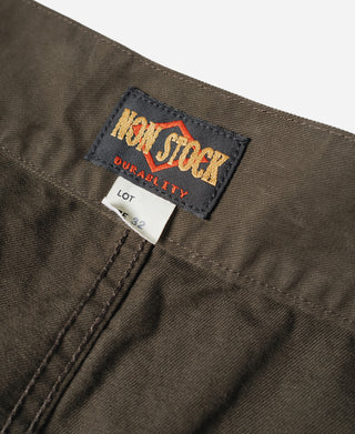 Brown combat pants fabric label patch with stitched hem and button placket