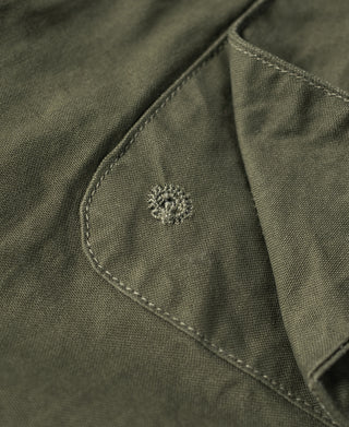 Olive fatigue jacket pocket with small embroidered emblem on stitched flap