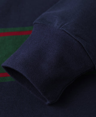 Rugby shirt sleeve cuff in navy knit with ribbed hem; green and red stripe nearby
