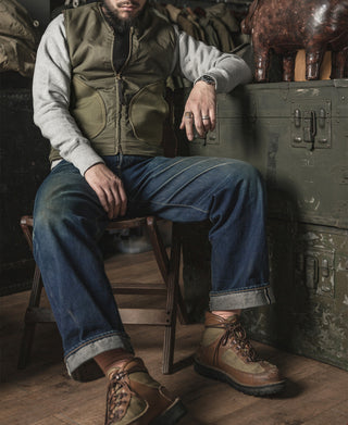 Olive pile-lined vest over a gray hoodie; side pockets and center zip visible