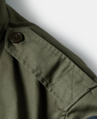 Olive flight jacket sleeve cuff with dark button and stitched pocket flap