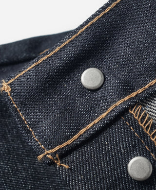 Indigo denim jeans front pockets with light silver buttons and tan stitched seams