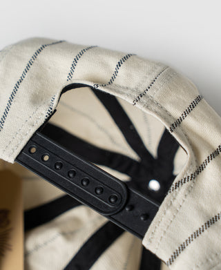 White newsboy cap interior with black adjustable strap and metal rivets