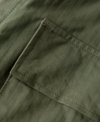 Olive fatigue trousers close-up of stitched cargo pocket panel and seams.