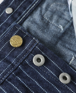 Indigo pinstripe pants close-up with snap buttons and cross-stitch pocket panel