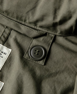 Olive parka waist tab with round button closure and stitched fabric