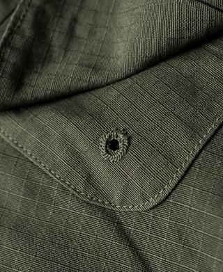 Olive jacket pocket flap with buttoned accent and embroidered emblem