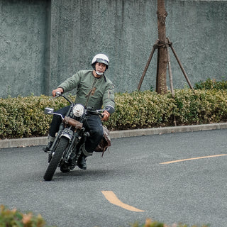 Olive MA-1 flight jacket on model riding a motorcycle, front zipper and collar visible