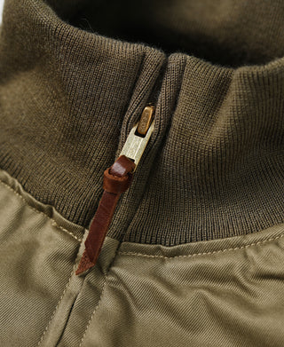 Olive ribbed collar zipper with brown leather pull and metal tag detail.
