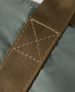 Brown webbing strap with stitched overlap on sage green bag