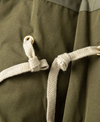 Olive parka close-up: hood drawstring with metal eyelets and knot detail