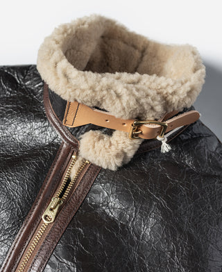 Flight jacket neck strap with tan shearling lining and metal buckle over brown leather