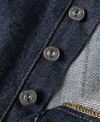 Dark blue denim jeans button fly area with three metal buttons and visible selvedge edge