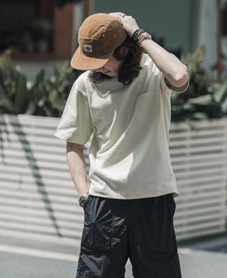 Khaki corduroy 5-panel cap worn with hands adjusting the brim