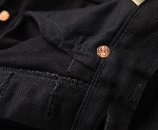 Black denim jeans close-up: front pocket flap and copper button
