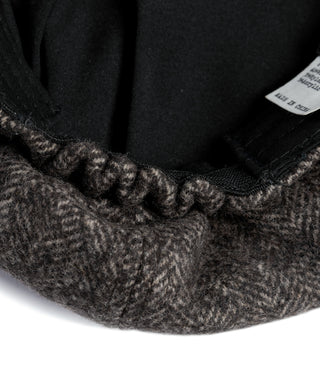 Black inner lining of dark gray herringbone newsboy cap with visible stitching.
