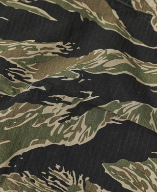 Tiger stripe camo fatigue pants fabric close-up with black, green, and tan pattern.