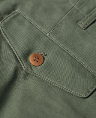 Olive trouser fly close-up with brown button and stitched pocket flap