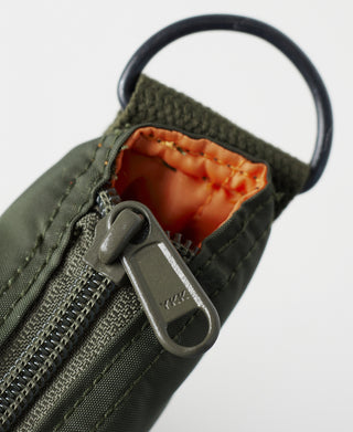Olive nylon bag zipper pull in pocket with orange fabric lining