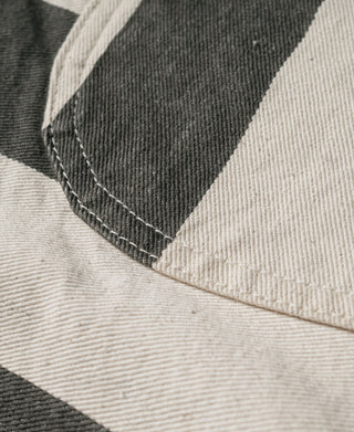 Wide striped prisoner pants hem close-up showing white and black panels with seam stitching.