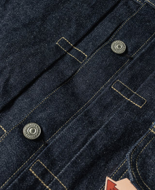 Indigo denim jacket front panel with metal buttons and yellow bar-tack stitching.