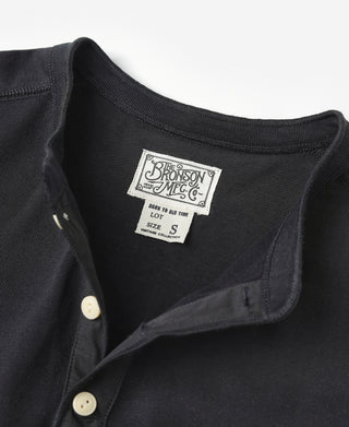 Black henley shirt neck label detail with cream button on placket.